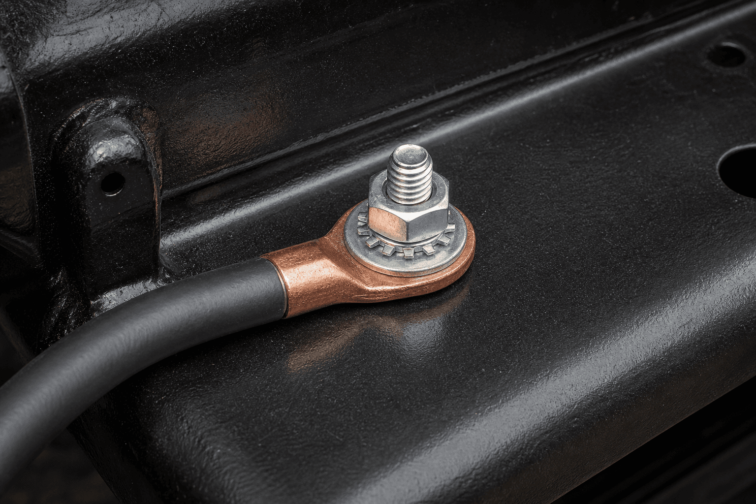 Black ground cable ring lug seated on a chassis stud and secured with a lock washer and nut